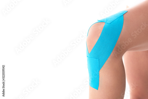Cropped view of kinesiology tapes on knee of woman isolated on white