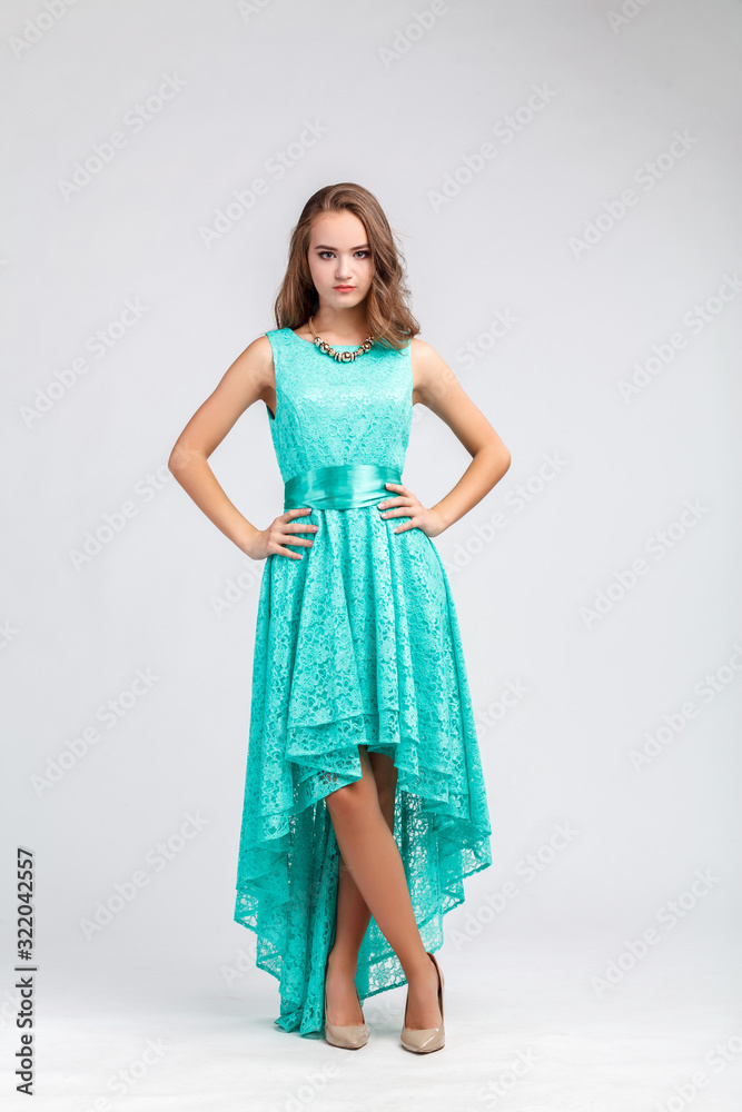 Beautiful young girl in long evening turquoise dress standing in full length, hands on hips, model Beautiful young girl in long evening turquoise dress standing in full length, hands on hips, model
