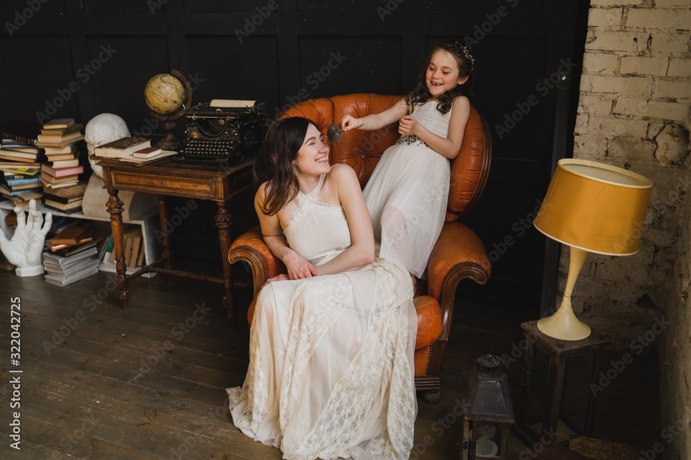 Obraz premium Mother and daughter hugging and playing together. Pretty little girl and beautiful woman. Girls in lace dresses playing in decorated room. Family weekend, beauty day, having fun, love concept.