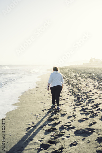 Back view of woman walking on sandy coast © Pabkov