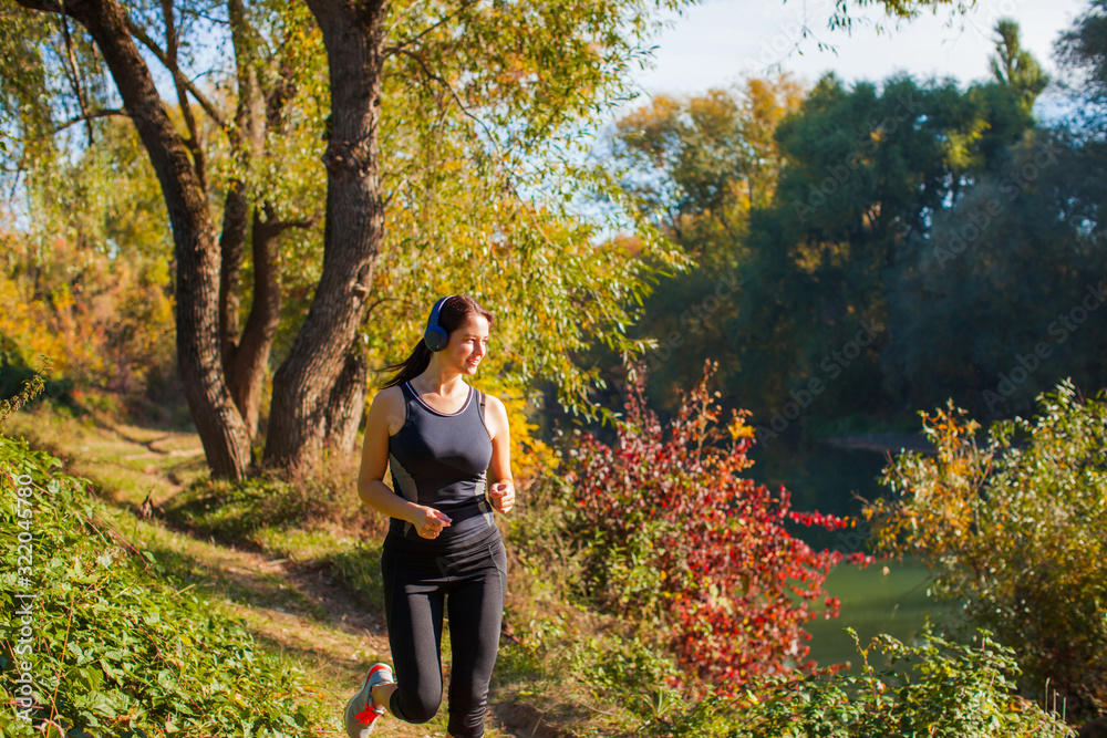Fototapeta premium Woman jogging and listening to music with wireless headphones
