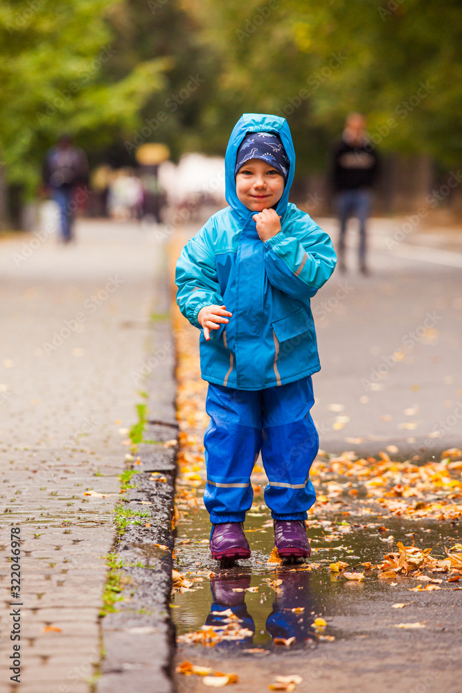 The boy rejoices in the puddle in the autumn park The boy rejoices in the puddle in the autumn park