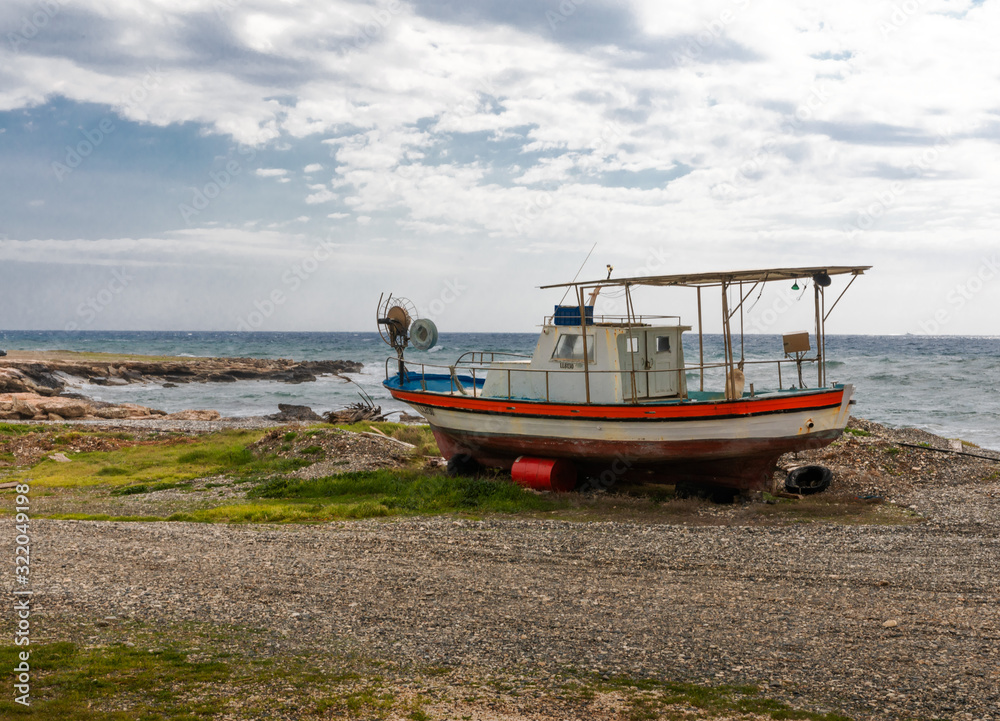 Old and broken wooden metal boat stranding on sea beach on island of Cyprus