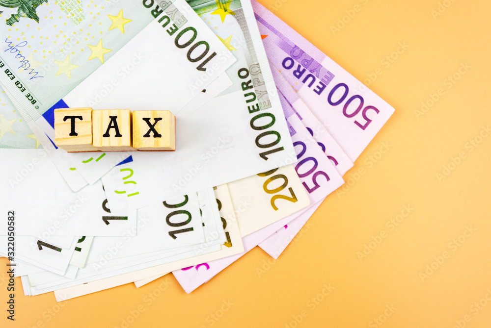 the word tax and the currency of the European Union of different denominations on an orange background 4