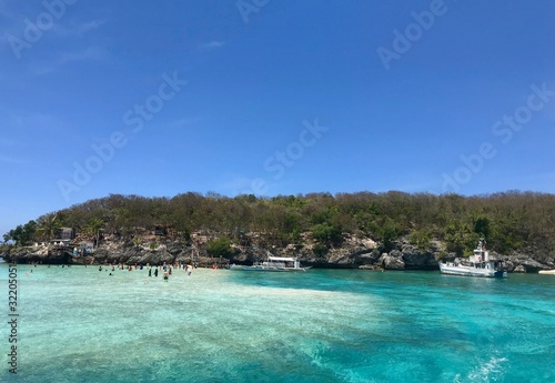 Scenic view over beach with boats and tourists  green and blue water  island in background  Cebu Island  Philippines