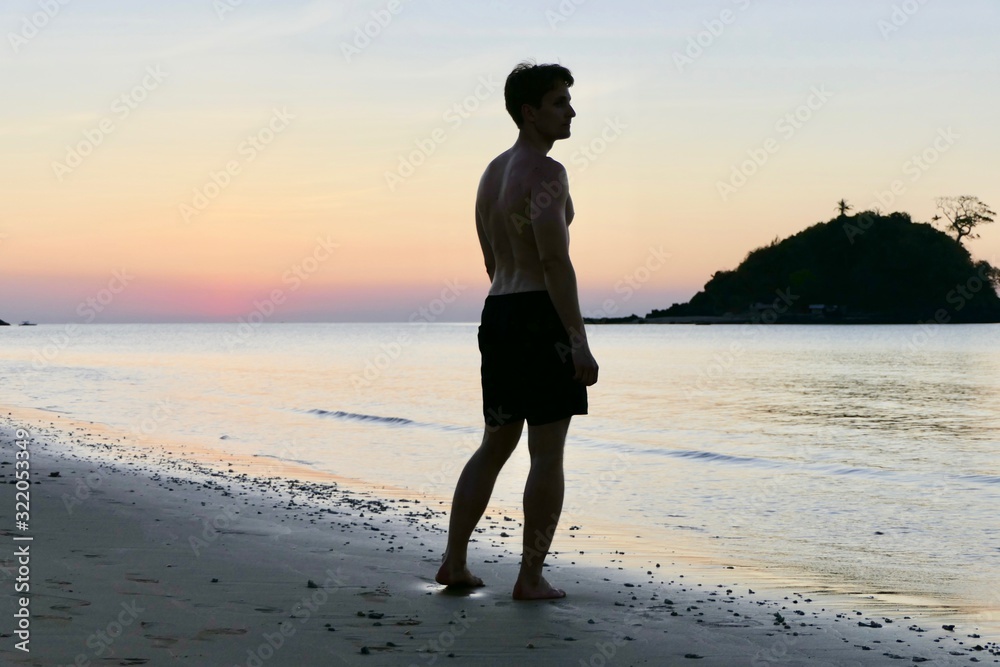 Man standing at Nacpan beach during sunset , before small island, El Nido, Palawan, Philippines