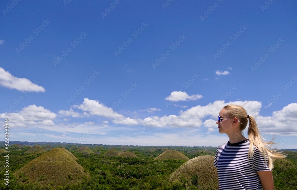 Blond woman before Chocolate Hills, looking into distance, Bohol, Philippines