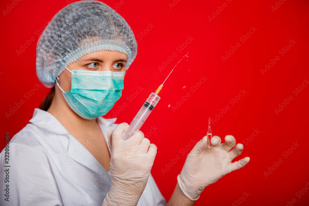 Close-up of a syringe with a stream of medicine from a needle in the hands of a female doctor on a red background. Close-up of a syringe with a stream of medicine from a needle in the hands of a female doctor on a red background.