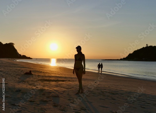 Silhouette of girl before sunset with orange sky at Nacpan beach, El Nido, Palawan, Philippines