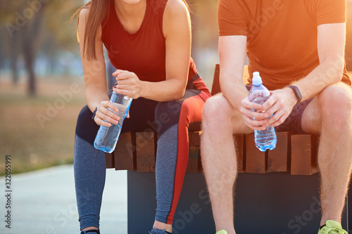 Modern couple making pause in an urban park during jogging / exercise.