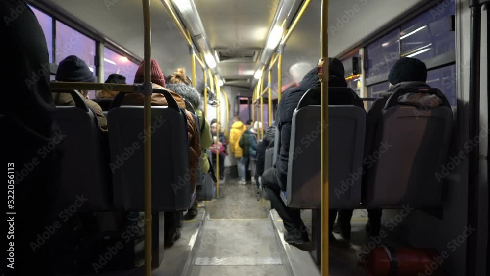 View inside the passenger compartment of the bus. The bus with people goes through the night city. Lights flash past the Windows. View from the back of the bus. Blurred background. 4K.
