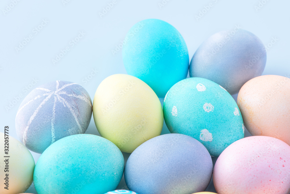 Colorful Easter eggs dyed by colored water isolated on a pale blue background, design concept of Easter holiday activity, close up, copy space.