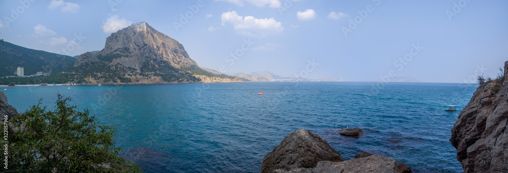 View of the Green Bay in the village of New World, coastal cliffs and a ridge of mountains on the horizon. View of Mount Falcon. Black Sea coast, Sudak region, Republic of Crimea