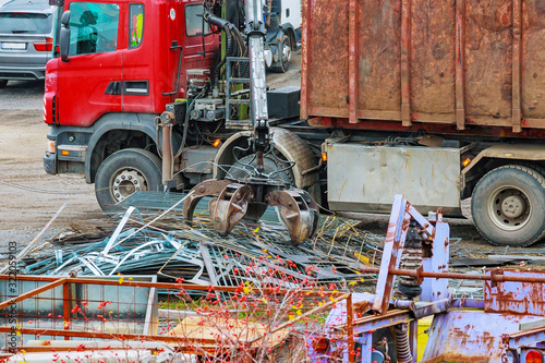 A grapple truck loads scrap industrial metal for recycling.