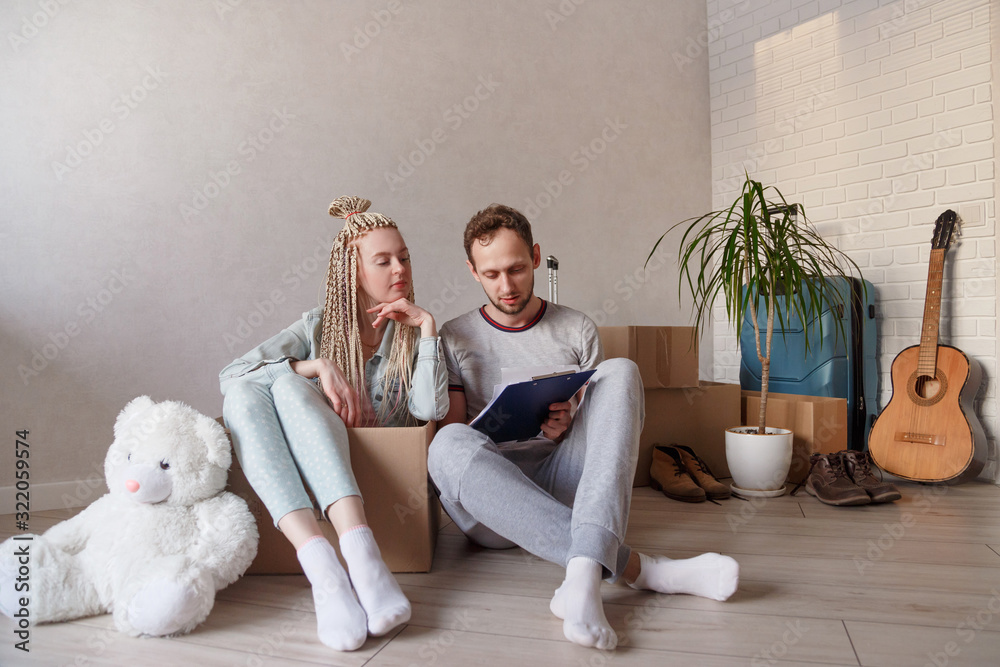 Young family takes an inventory of things during the move. a man with a folder records the nomenclature of collected things. Young family takes an inventory of things during the move. a man with a folder records the nomenclature of collected things.