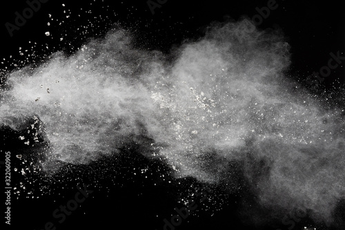 Plakat White powder explosion isolated on black background.White dust particles splash.