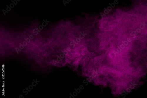 Purple color powder explosion cloud  on black background.Purple dust particles splash.