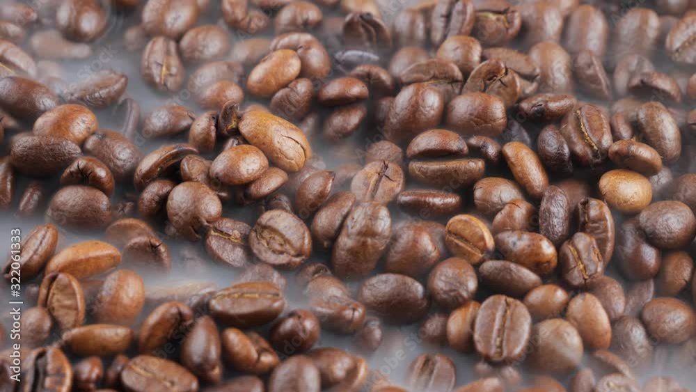 Black coffee beans roast in a pan in the smoke