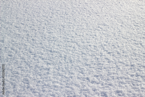 Snow background. Fresh snow. Texture of white snow sparkling in the sun. Abstract christmas blurred background.