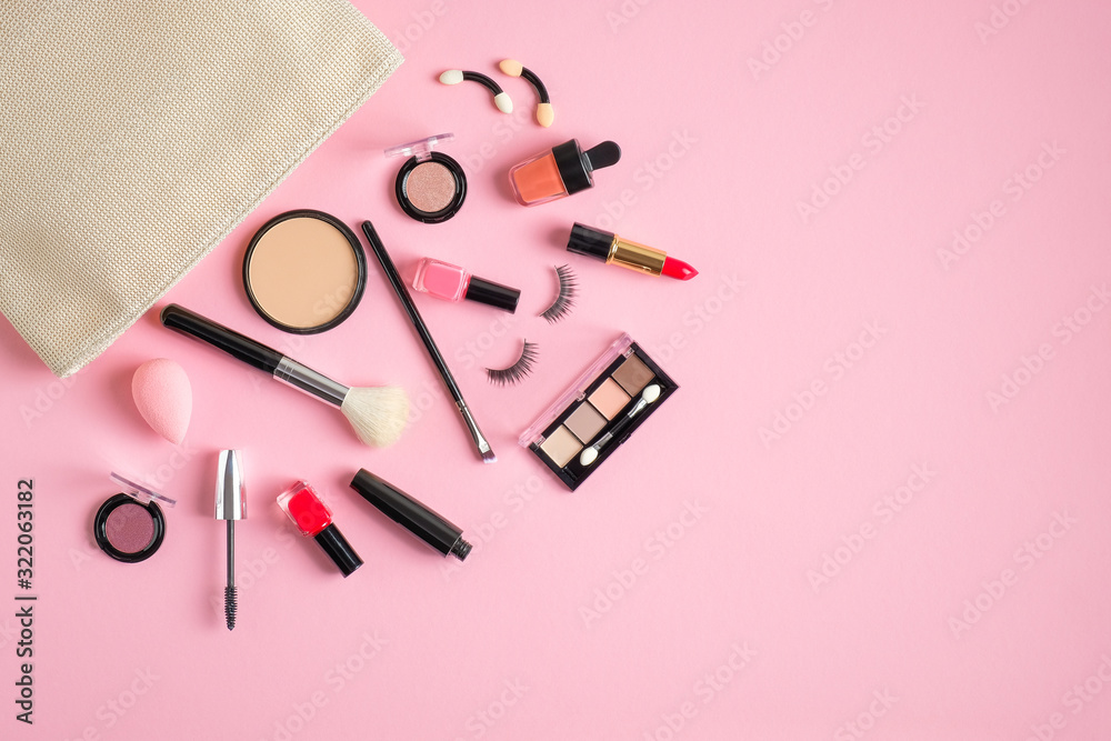 White makeup bag with cosmetics beauty products spilling out on to pastel pink background. Flat lay, top view White makeup bag with cosmetics beauty products spilling out on to pastel pink background. Flat lay, top view