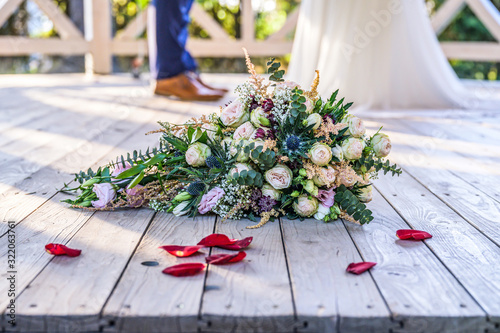 Wedding bouquet in front of newlyweds wedding couple inbackground, kissing or holding hands in love Shallow depth bokeh photo