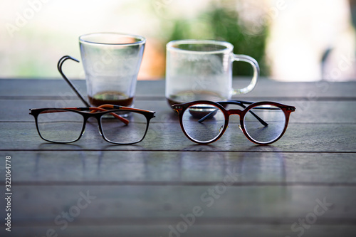 Blurred 2 eyeglasses, Blurry 2 Coffee glasses cups with coffee stains stuck on them, then after drinking it on wooden table in bokeh blurred green garden background, Close up shot, Selective focus