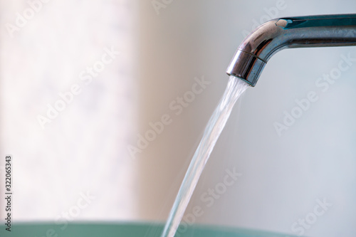 Water flowing from faucet to green washbasin  Bathroom concept