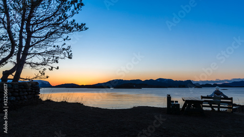 ULSTEINVIK  NORWAY - 2018 FEBRUARY 28. Lonely person sit on the bench and view the beautiful sunset