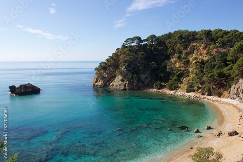 Alonaki beach in Preveza near Parga with sandy beach and a big rock in the blue sea, in a pine trees forest. Background view of horizon and blue sky © Giorgos Karagiannis
