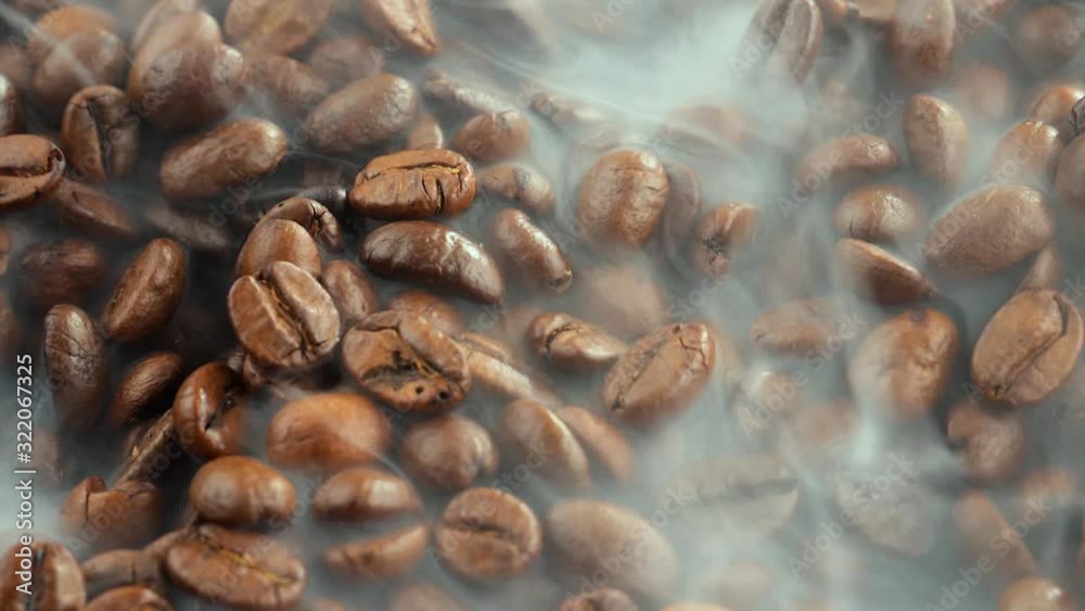 Black coffee beans roast in a pan in the smoke