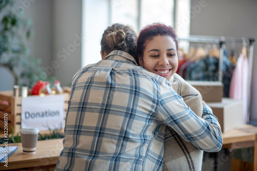 Man in plaid shirt hugging young smiling girl.