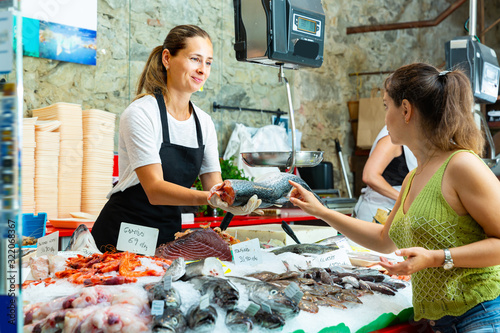 Polite female offering chilled salmon to woman photo