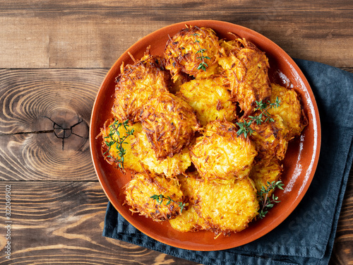 Potatoes pancakes latkes, flapjacks, hash brown or potato vada on brown wooden table. Top view or flat lay. Copy space for text. photo