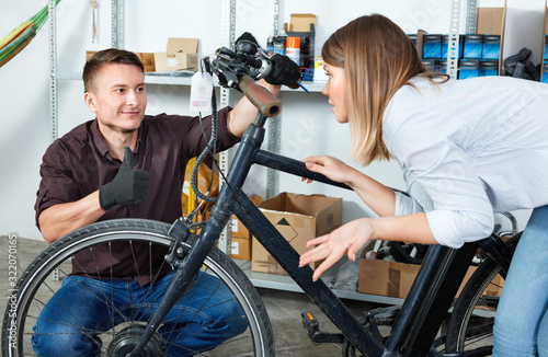 Man with woman are lubricating the bicycle mechanism with silicone in the workshop.