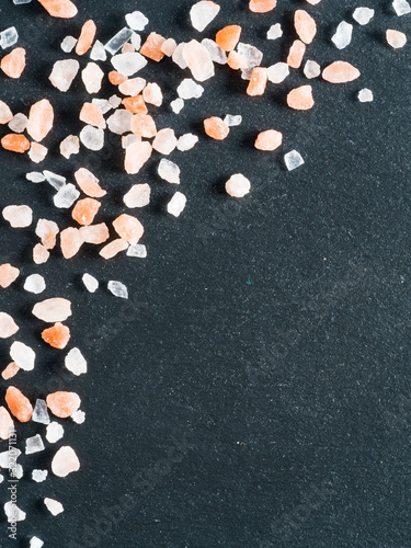 Himalayan pink salt in crystals on black stone background. Copy space photo