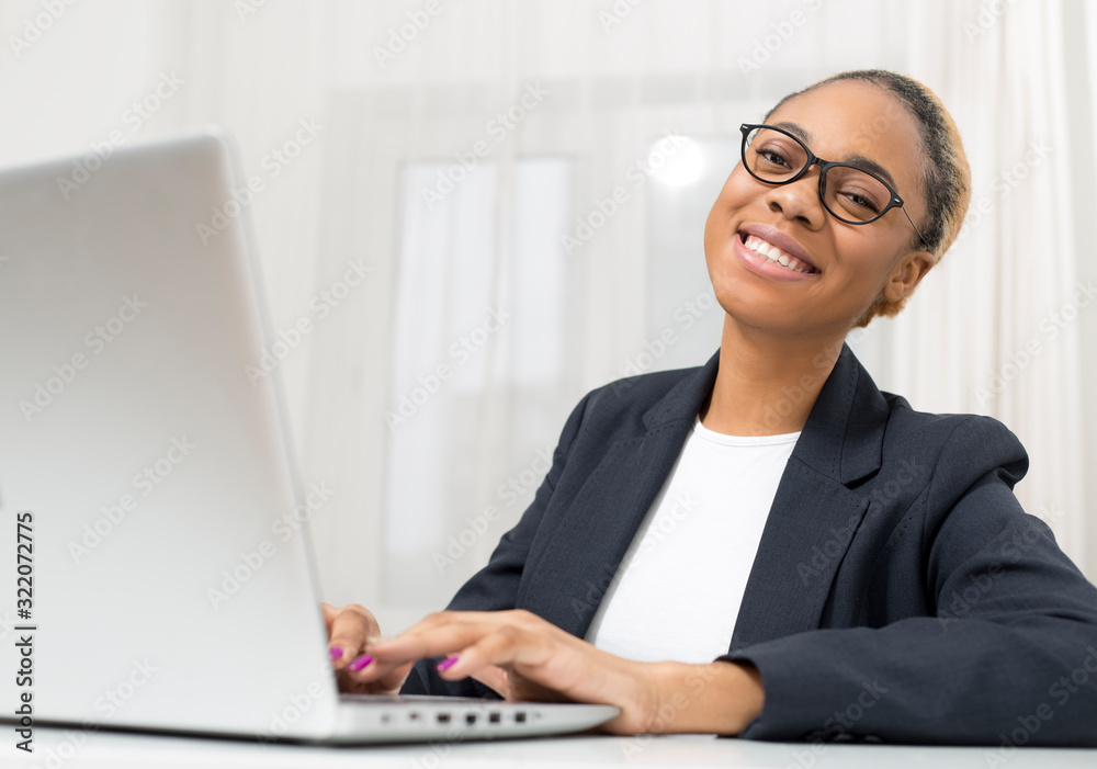 Business African American young woman working in office at laptop. Black girl manager uses a computer in the workplace. Business African American young woman working in office at laptop. Black girl manager uses a computer in the workplace.