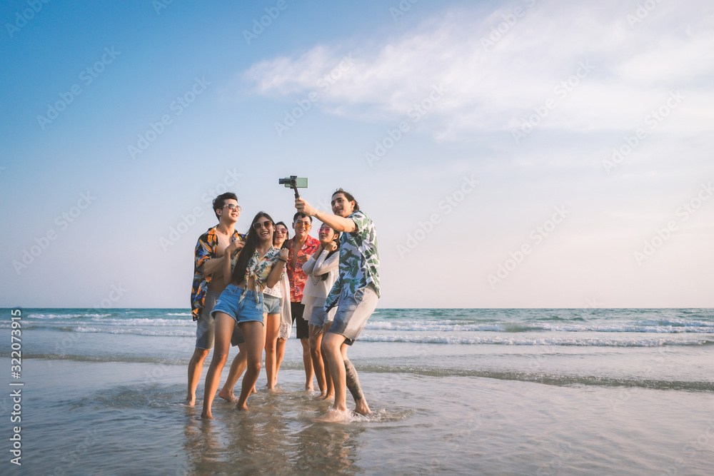 A group of happy friends having enjoy playing selfies on the beach amid the blue sky. - obrazy, fototapety, plakaty 