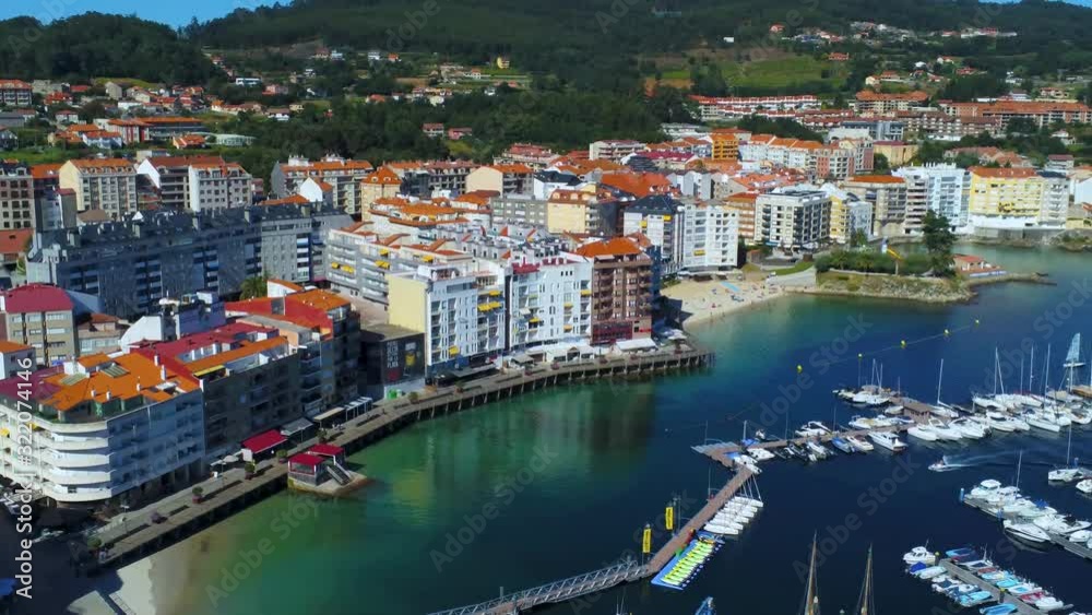 Aerial view of beautiful seaside city of Sanxenxo in Spain, with buildings and promenade on harbor with calm blue turquoise lagoon Aerial view of beautiful seaside city of Sanxenxo in Spain, with buildings and promenade on harbor with calm blue turquoise lagoon