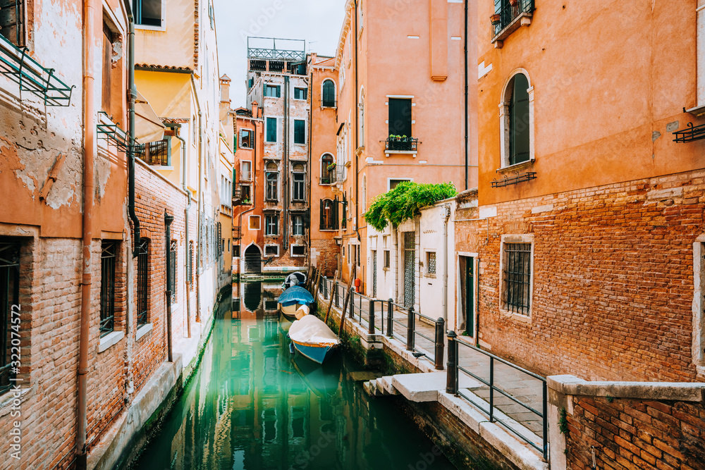Venice Italy. Canal with old typical orange facade houses, patio and windows