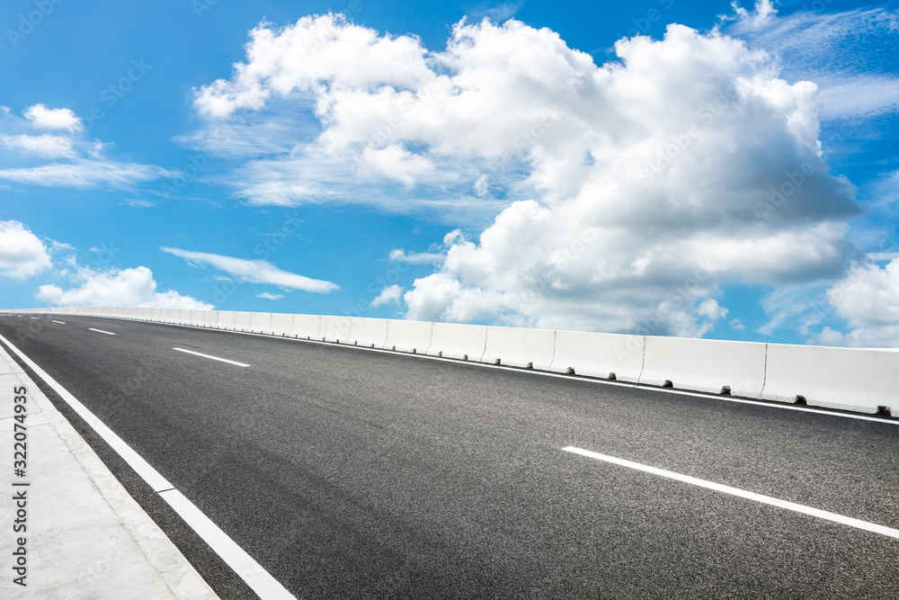 Fototapeta premium Empty asphalt road and blue sky with white clouds in summer