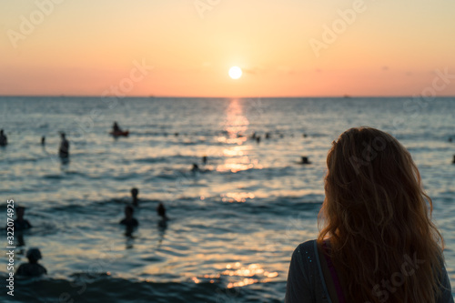Girl on the beach looks at the sunset. © Hryhorii