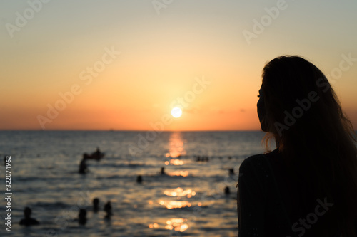 Girl on the beach looks at the sunset.