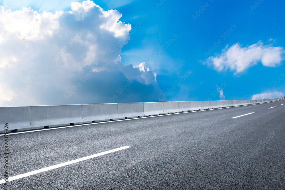 Fototapeta premium Empty asphalt road and blue sky with white clouds in summer