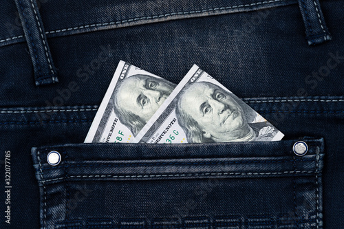 One hundred dollar banknote money in pocket jeans pants background texture. 100 dollar bill close up photo