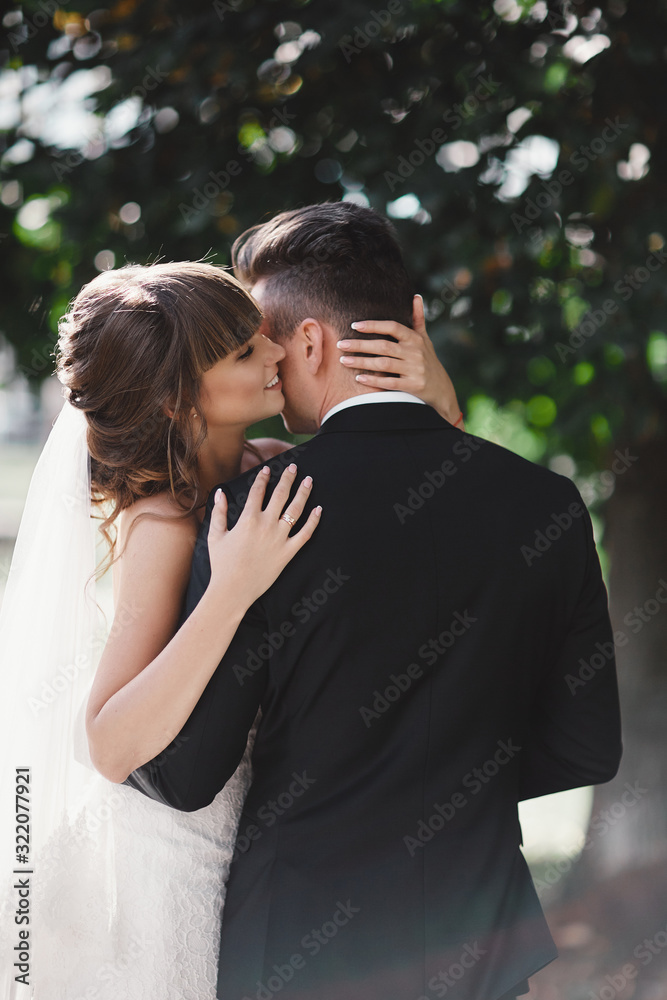 gorgeous young bride and stylish groom are hugging on wedding day outdoors, wedding couple, luxury wedding.