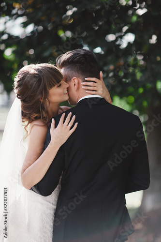 gorgeous young bride and stylish groom are hugging on wedding day outdoors, wedding couple, luxury wedding. © Andriy Medvediuk