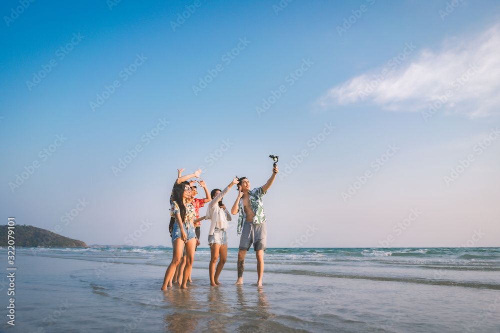 A group of happy friends having enjoy playing selfies on the beach amid the blue sky. - obrazy, fototapety, plakaty 