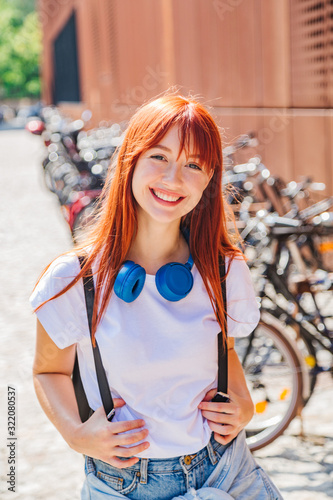 Cute redhead girl having fun on street near bikes