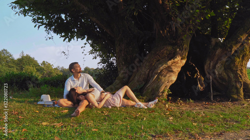A man and a woman rest under a tree in the summer.