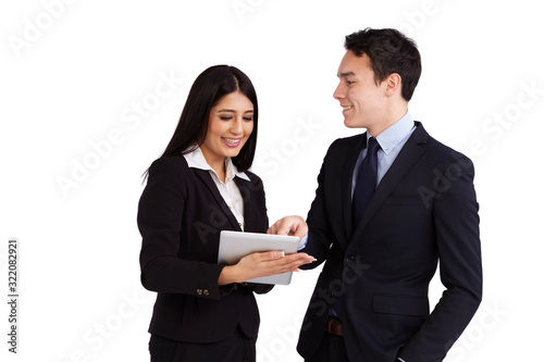 A young business man is pointing at a tablet with a young business woman. Both of them are smiling.